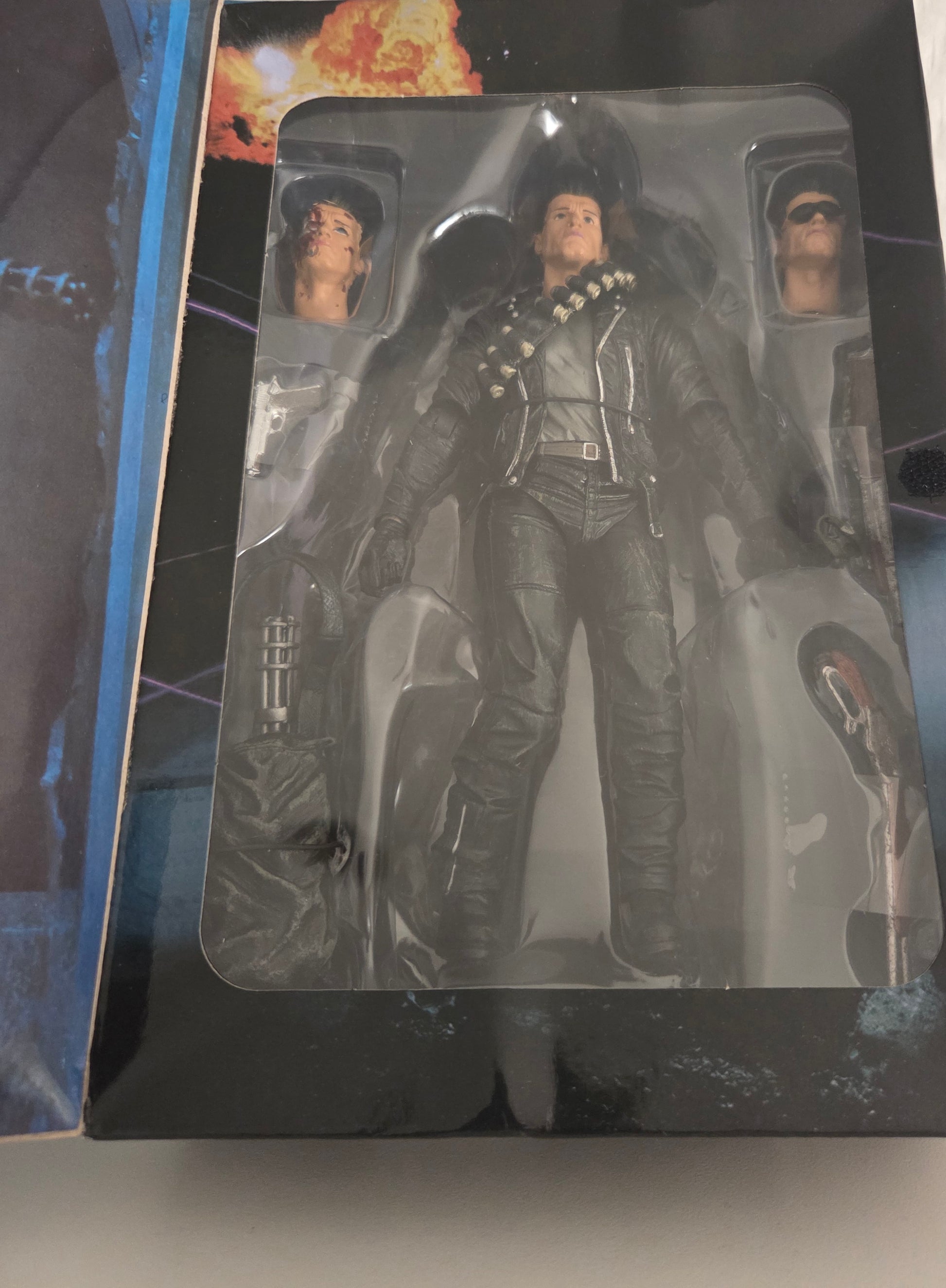 Figurine T-800 NECA Terminator 2 dans son blister ouvert – vue d'ensemble avec les 3 têtes interchangeables et accessoires