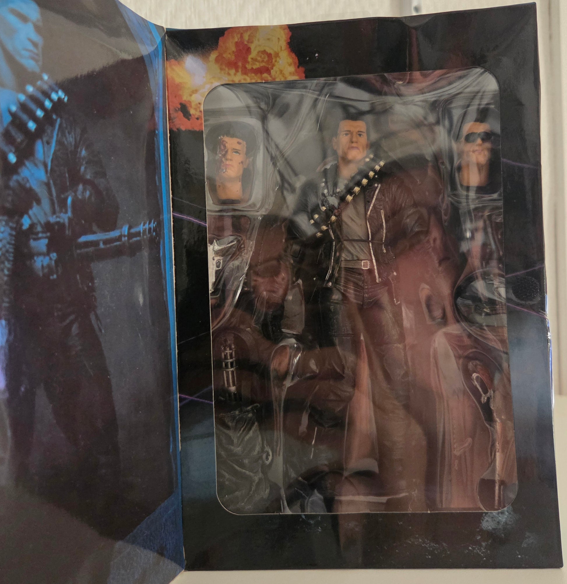 Figurine T-800 NECA Terminator 2 dans son blister ouvert – vue d'ensemble avec les 3 têtes interchangeables et accessoires